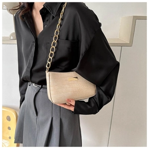 Detail of beige croc-embossed leather underarm bag with thick gold chain on model