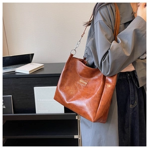 Détail du sac cabas en similicuir marron avec bandoulière chaîne et étiquette mode