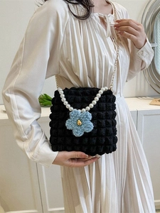 Chic black bubble tote bag with pearl handle and blue flower pendant on white dress