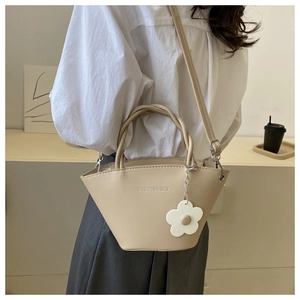 Chic apricot bucket bag with floral charm and shoulder strap shown on a model