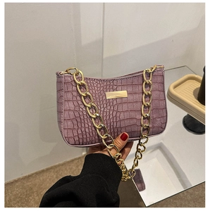 Close-up of purple faux leather underarm bag with crocodile texture and golden chain