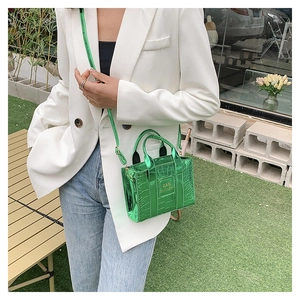 Glossy green crocodile texture mini tote bag shown as a crossbody on a stylish model