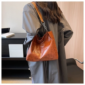 Détail du sac cabas en cuir marron avec chaîne argentée et étiquette de mode sur un mannequin
