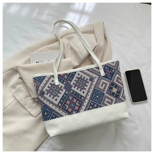 Flat lay of ethnic tote bag with colorful geometric patterns on a white fabric surface