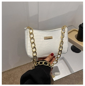 Detailed macro view of white crocodile pattern PU leather and chunky gold chain