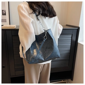 Détail d'un sac cabas bleu foncé avec texture vintage et bandoulière en chaîne