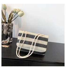 Detail of striped woven tote bag with rope handles on a wooden table with tulips