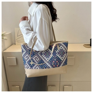 Close-up of ethnic woven geometric patterns and durable beige leather trim on tote bag