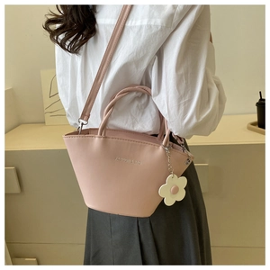 Detail of pink fashion basket bag with flower charm worn as a crossbody by a model