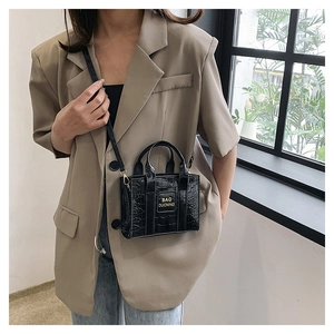 Detail of black faux crocodile leather mini tote bag with adjustable shoulder strap