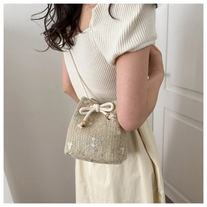 Détails de broderie florale en dentelle sur sac seau en paille avec cordon