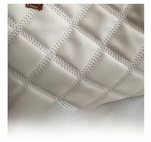 Close-up of precise diamond quilting and stitching on beige leather tote bag