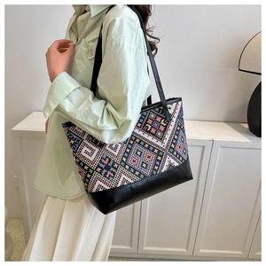 Detail of colorful geometric woven pattern and black leather texture on a large tote bag