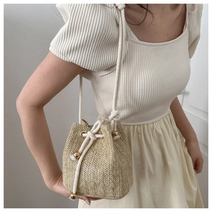 Detail of woven straw bucket bag with cotton drawstring and gold metallic hardware