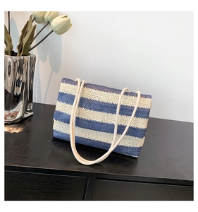 Detail of striped woven tote bag with rope shoulder strap on a modern black cabinet