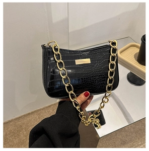 Detail of black faux crocodile skin bag with chunky gold chain strap and metal logo plate