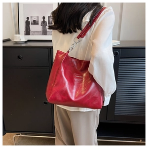 Détail d'un sac cabas bordeaux avec chaîne argentée présenté dans un cadre de vie