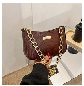 Detailed macro view of the brown crocodile pattern texture and gold chain strap of the bag