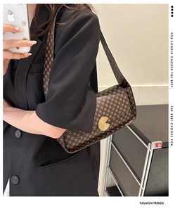 Détail d'un sac bandoulière vintage avec boucle dorée sur un mannequin en blazer noir