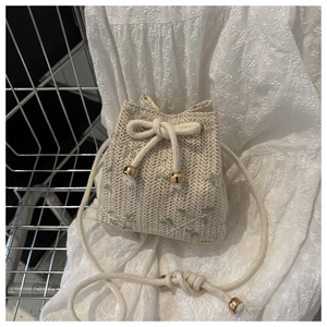 Détail du sac seau tissé avec broderies florales et cordon de serrage aux embouts dorés