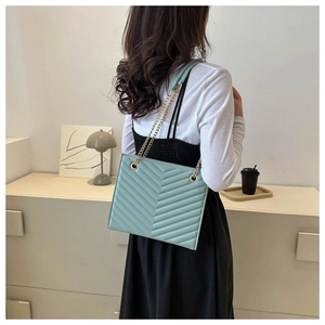 Rear view of a model wearing the mint green quilted leather tote bag with a gold chain strap