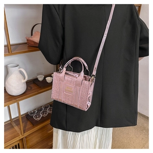 Detail of pink croc-embossed metallic handbag with dual handles and logo branding