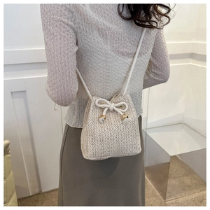 Model view of cream woven bucket bag with adjustable drawstring and rope strap detail