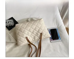 Beige quilted tote bag with brown straps shown from above with lifestyle accessories