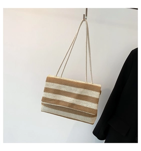 Detail of striped woven tote bag with round rope straps hanging against a white wall