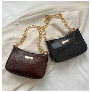 Detail of crocodile pattern underarm bags with gold chain straps in brown and black colors