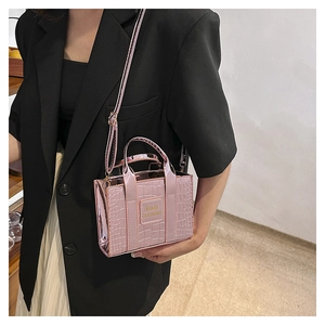 Detail of metallic pink mini handbag with crocodile texture and adjustable strap