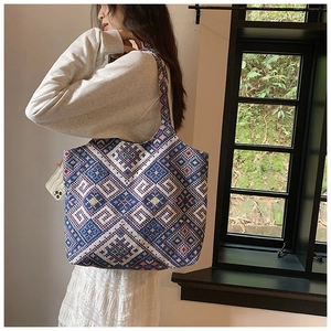 Detail shot of ethnic woven tote bag with blue and white geometric patterns on a model