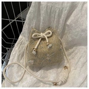 Détails de broderie et texture de paille tressée sur ce sac seau d'été à cordon