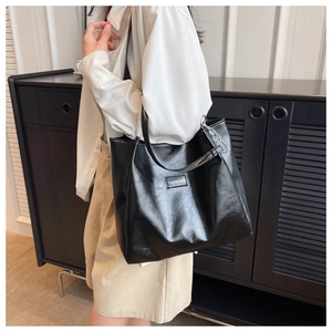 Détail d'un sac cabas noir en similicuir avec chaîne et étiquette de mode cousue