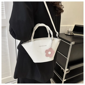 Close-up of a white bucket bag with 'FASHION & BAG' text and a pink flower charm