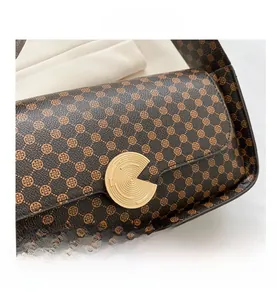 Détail d'un sac à bandoulière en cuir vintage marron avec motif et boucle dorée