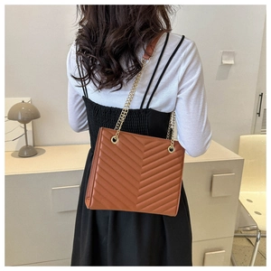 Brown quilted leather tote bag with gold chain strap shown on a model's shoulder