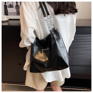 Vue détaillée du cabas en cuir noir brillant avec chaîne argentée et logo mode