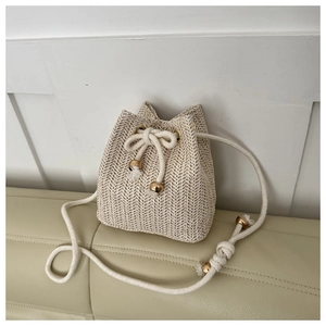 Detailed view of woven straw bucket bag with cotton drawstring and gold bead accents