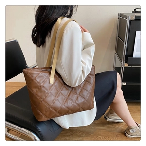Detail of brown quilted tote bag with wide leather strap and matte finish texture