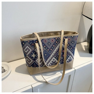 Detail view of ethnic geometric jacquard fabric and PU leather straps on the tote bag