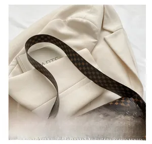 Détail d'un sac bandoulière vintage avec fermoir doré circulaire et large bandoulière