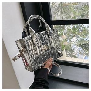 Detail of silver crocodile pattern tote bag with metallic logo and adjustable strap