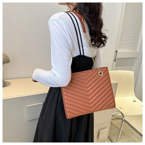 Detail of caramel quilted shoulder bag with chain strap shown on a model side view