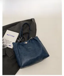 Détail du sac cabas bleu en cuir avec fermoir magnétique et plaque en métal doré