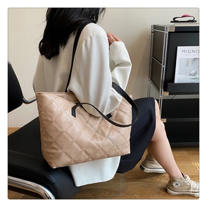 Detail of quilted leather tote bag with elegant diamond stitching and black shoulder strap