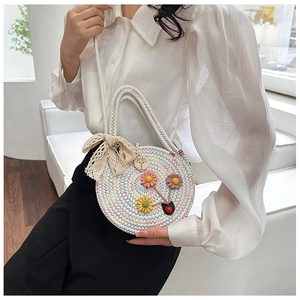 Détail d'un sac rond en paille avec fleurs 3D colorées et un nœud en dentelle fine