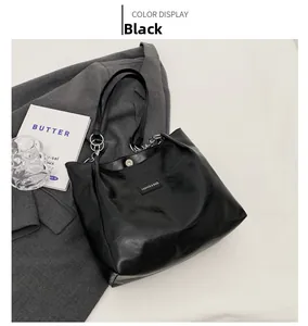 Détail du cabas en cuir PU noir avec bandoulière chaîne argentée et étiquette mode