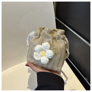 Detailed close-up of handmade woven straw mini bucket bag with a white floral ornament