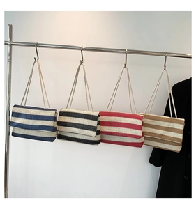Detail of four striped woven tote bags in navy, black, red and brown on a metal display